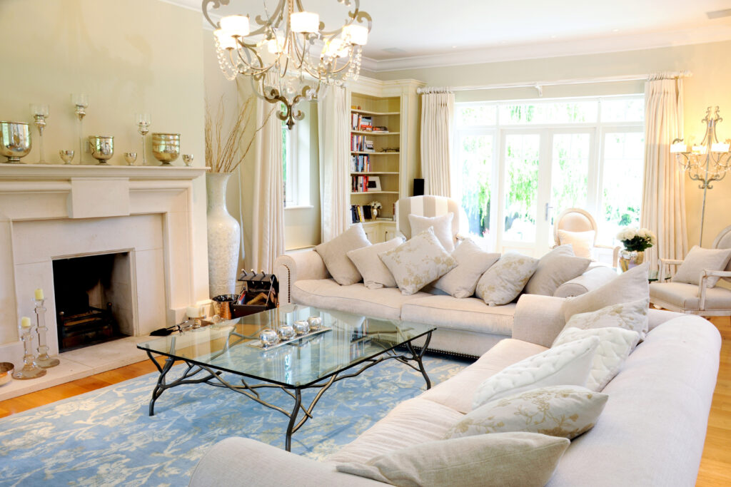 A bright living room with a chandelier, fireplace and cream sofas